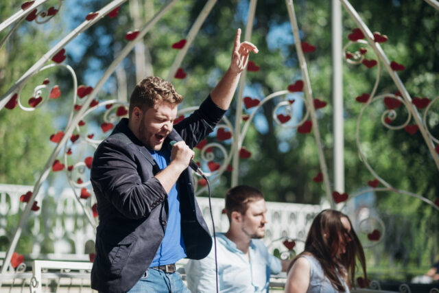 man singing into a microphone at outdoor event
